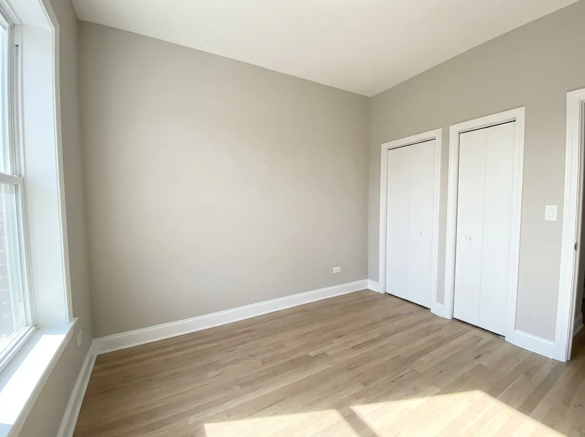 Recámara de apartamento pintada en gris claro con puertas de clóset blancas